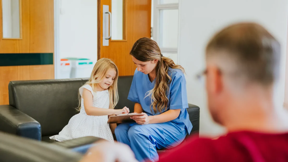 Nurse in conversation with a young patient and parent