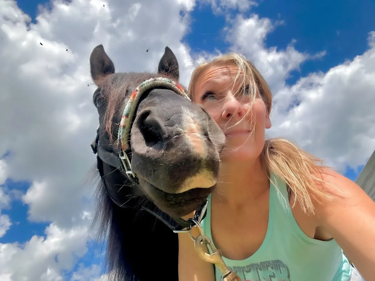 Jean Storie taking a selfie with her black horse under a blue sky