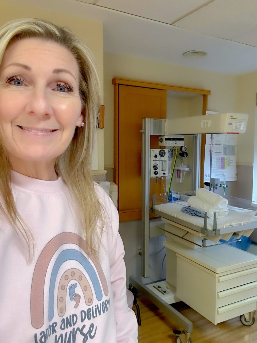Jean Storie wearing a Labor and Delivery Nurse sweatshirt in a hospital nursery
